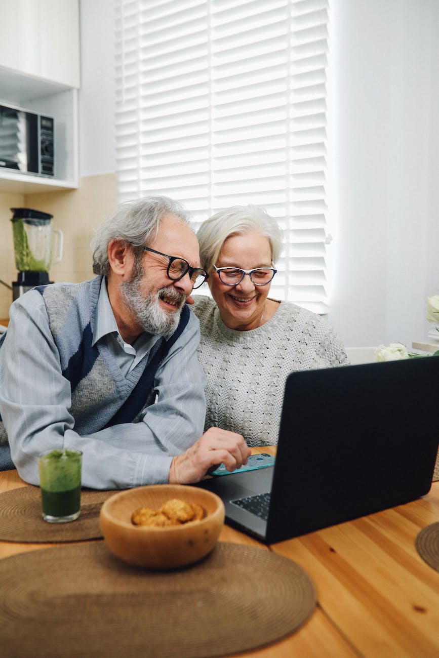 senior couple smiling and using a laptop