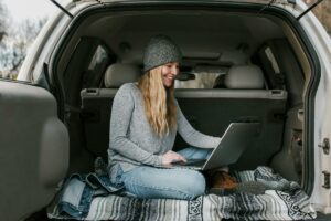 woman in gray sweater and blue denim jeans sitting on car seat